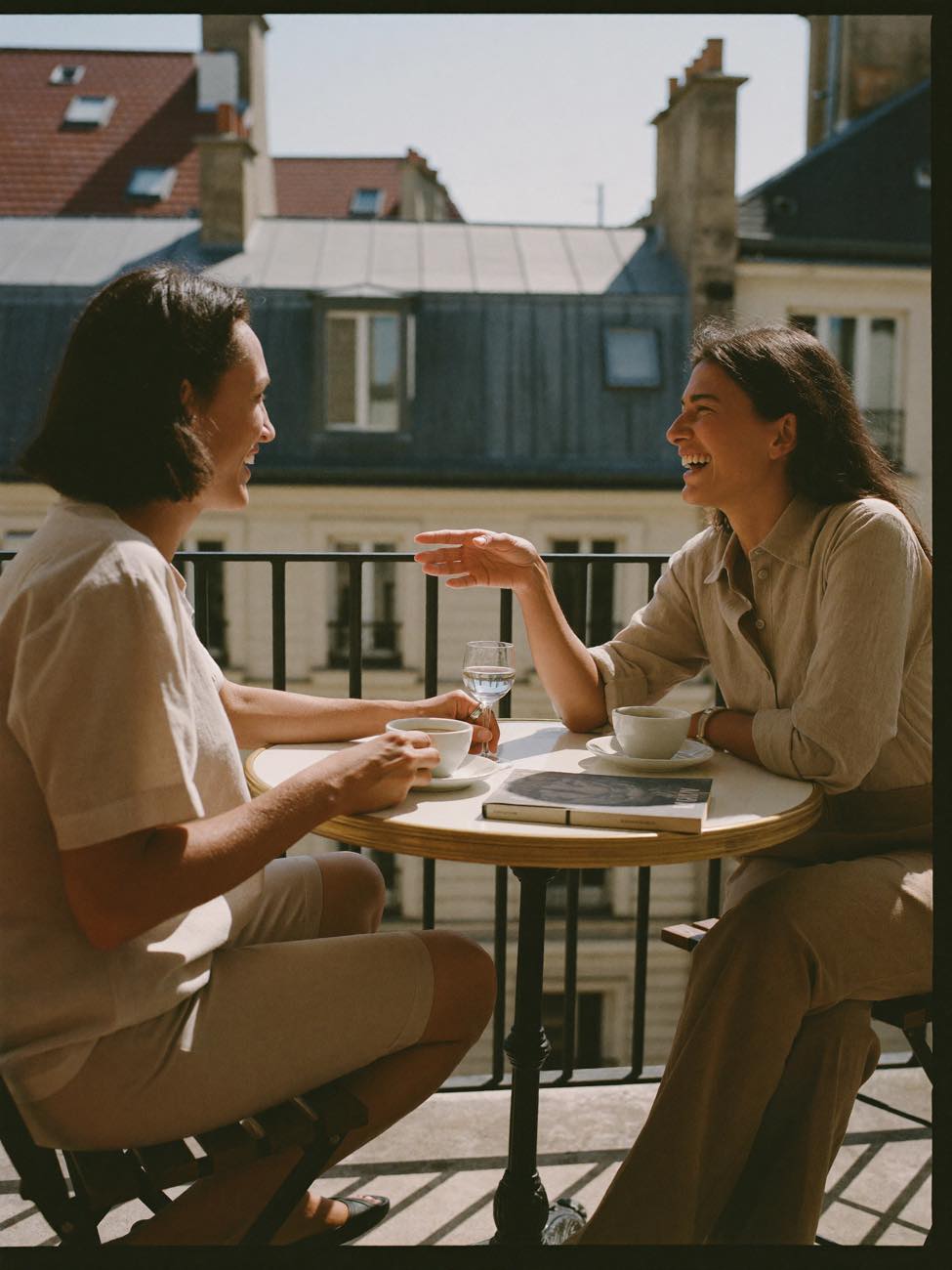 Two friends talking over coffee on a sunlit balcony