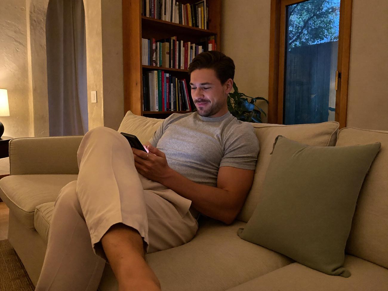 A man taking an assessment on his phone at home in warm evening light